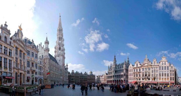 People enjoying the lively Brussels city square with historic architecture under a blue sky, 2K Desktop Wallpaper