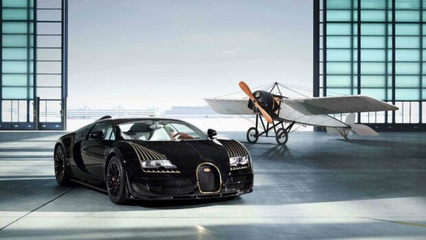 A black Bugatti Veyron stands inside a large hangar next to a vintage propeller airplane, 2K Desktop Wallpaper