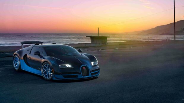 A sleek Bugatti Veyron is parked near the beach at sunset with the ocean and mountains in the background, 4K Desktop Wallpaper