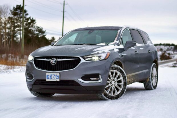 A gray Buick Enclave is driving on a snowy road with some snow on its hood and tires, HD Desktop Wallpaper