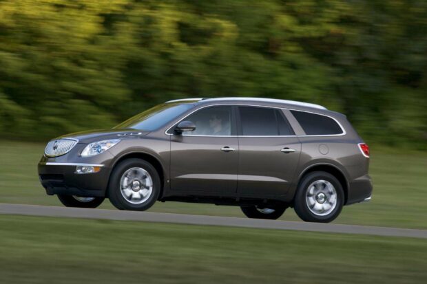 A brown Buick Enclave is driving past green trees on a sunny day, HD Desktop Wallpaper