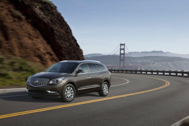 A Buick Enclave is driving along a curved coastal highway with cliffs and the Golden Gate Bridge in the background, 2K Desktop Wallpaper