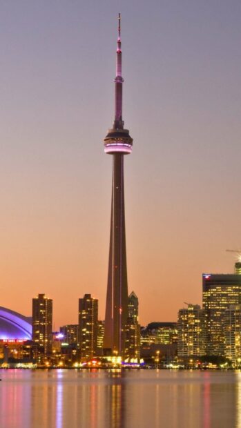 The CN Tower in Canada stands tall with city lights reflecting on the water at sunset, 2K Phone Wallpaper