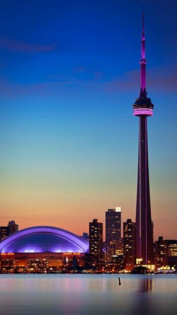 The CN Tower in Canada is lit up in purple against the evening sky with the city skyline below, HD Mobile Wallpaper