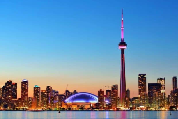 The CN Tower in Canada lights up the city skyline during dusk with colorful illumination, HD Desktop Wallpaper