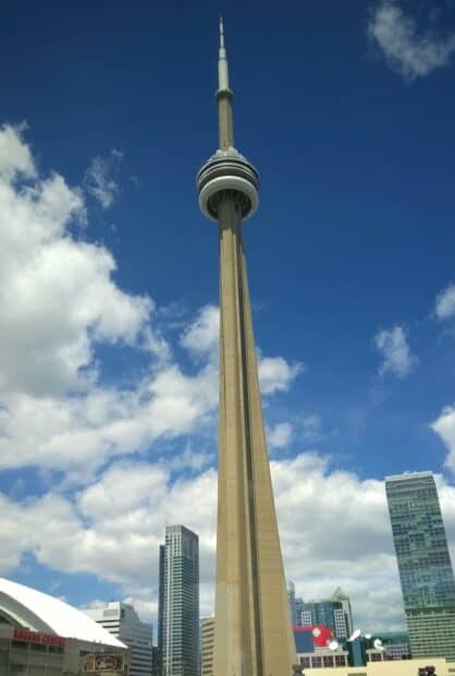 The CN Tower Canada stands tall against a partly cloudy sky with surrounding city buildings, 2K Mobile Wallpaper
