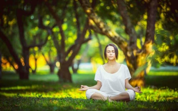 A woman practices yoga meditation outdoors in a peaceful park setting, 2K Desktop Wallpaper