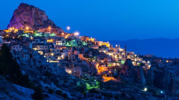 The Cappadocia landscape glows with warm lights under a deep blue twilight sky, HD Desktop Wallpaper