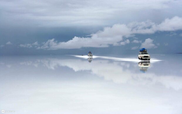 Two vehicles are reflected on the vast salt flats under a cloudy sky in Bolivia, HD Desktop Wallpaper