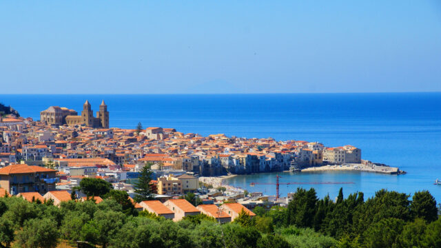 Cefalu Coastal Town View With Cathedral And Blue Sea Background