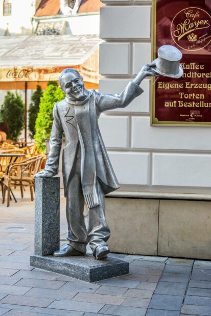 A smiling statue tipping his hat on a Bratislava street near a cafe, HD Desktop Wallpaper