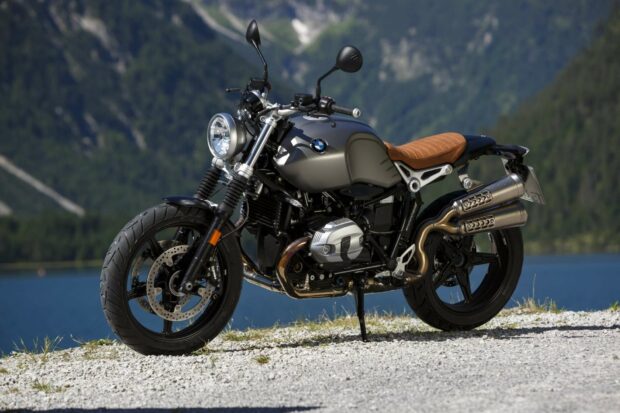 The BMW R Nine T motorcycle is parked on a gravel surface with a lake and mountains in the background, HD Desktop Wallpaper
