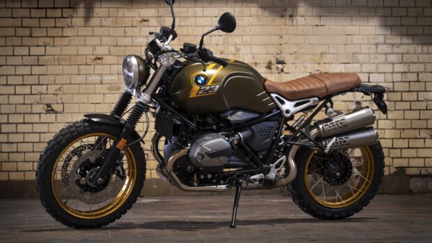 A BMW R Nine T motorcycle with gold rims and a leather seat parked indoors near a brick wall, 2K PC Wallpaper