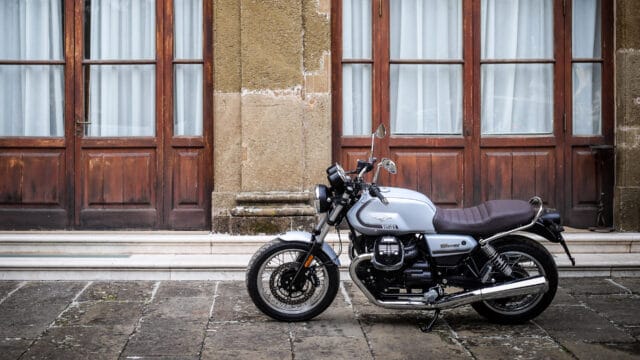 Classic Moto Guzzi V7 Motorcycle Parked by Vintage Wooden Doors Wallpaper