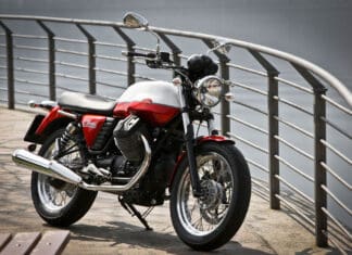 Classic Moto Guzzi V7 Motorcycle Parked by Waterfront with Metal Railings Wallpaper
