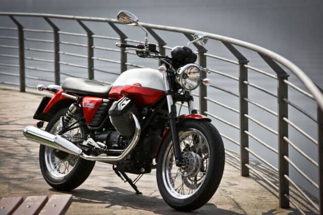 Classic Moto Guzzi V7 Motorcycle Parked by Waterfront with Metal Railings Wallpaper