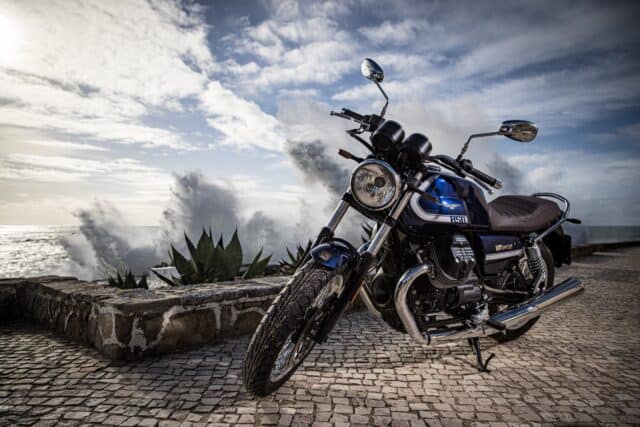 Classic Moto Guzzi V7 Motorcycle Wallpaper with Ocean Waves Background