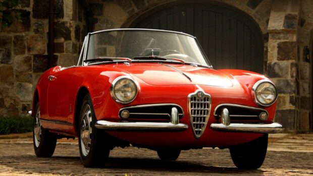 A classic red Alfa Romeo convertible is parked in front of a stone garage door, HD Desktop Wallpaper