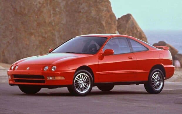 A red classic Honda Integra is parked on a road near rocky cliffs by the sea, HD Desktop Wallpaper