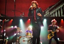 A classic rock band is performing live in front of bright stage lights with energetic atmosphere during a concert, 4K Desktop Wallpaper