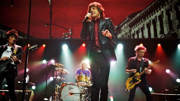 A classic rock band is performing live in front of bright stage lights with energetic atmosphere during a concert, 4K Desktop Wallpaper
