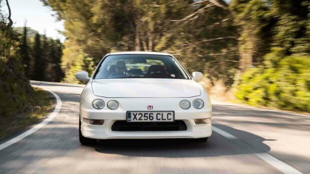 A white Honda Integra is driving down a winding road surrounded by trees and greenery, HD Desktop Wallpaper