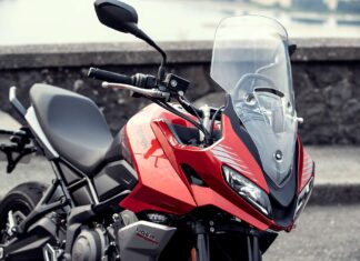 Close up view of red Triumph Tiger Sport 660 motorcycle parked by stone wall wallpaper