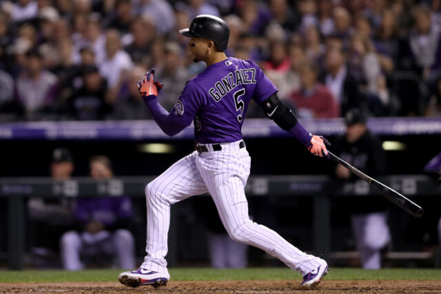 Colorado Rockies Player Swinging Bat During Night Game Wallpaper