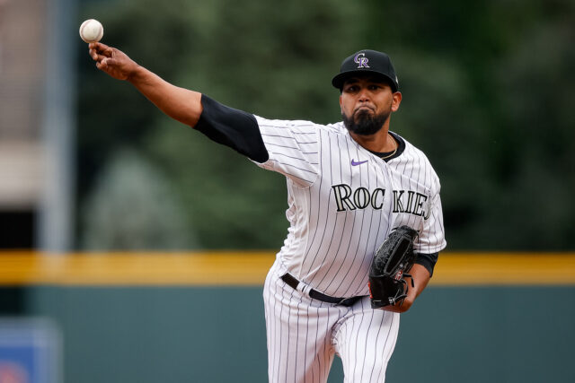 Colorado Rockies pitcher delivering a powerful pitch in stadium action wallpaper
