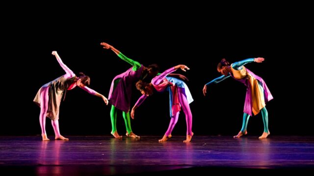 Colorful Contemporary Dance Performance on Dark Stage Artistic Movement Wallpaper