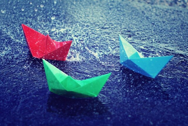 Colorful Paper Boats on Rainy Water Surface Wallpaper