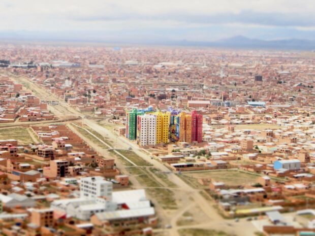 A cluster of colorful high rise buildings stands out prominently in a sprawling Bolivian cityscape, 2K Desktop Wallpaper