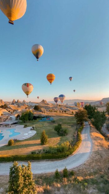 Several hot air balloons float over the unique rock formations and fields of Cappadocia at sunrise, HD Phone Wallpaper