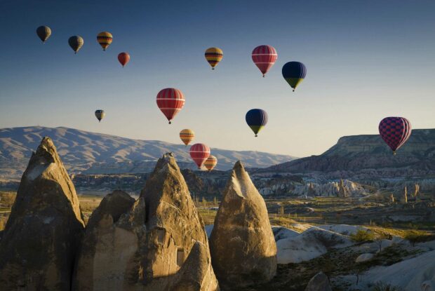 A scenic view of Cappadocia with hot air balloons flying over unique rock formations, HD Desktop Wallpaper