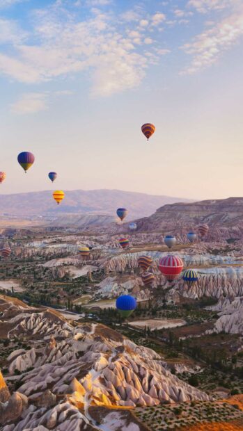 A scenic view of colorful hot air balloons flying above the rocky formations in Cappadocia, HD Mobile Wallpaper