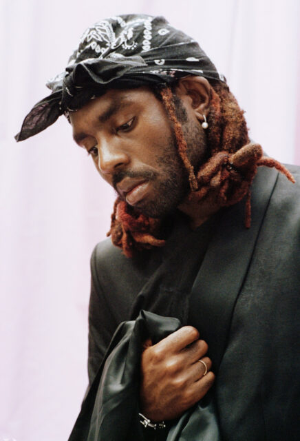 Contemplative Dev Hynes In Stylish Headscarf Portrait Wallpaper