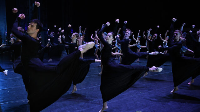 Contemporary Dance Group Performing Dynamic High Kicks on Stage Wallpaper