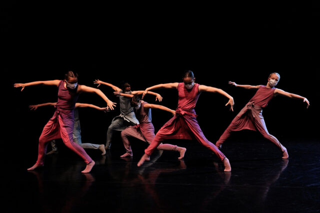 Contemporary Dance Performance with Masked Dancers in Dynamic Movement on Dark Stage