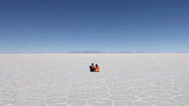 Couple Sitting on Endless Salt Flats at Salar De Uyuni Bolivia Wallpaper