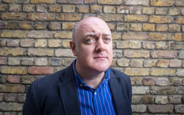 Dara O Briain Standing Against Brick Wall Wallpaper