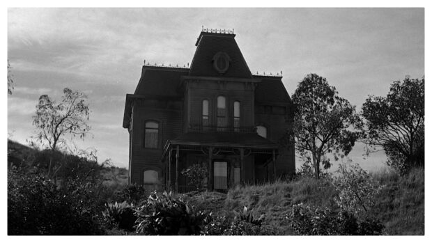 A dark gothic house sits isolated on a hill under a cloudy sky in this Alfred Hitchcock scene, HD Desktop Wallpaper
