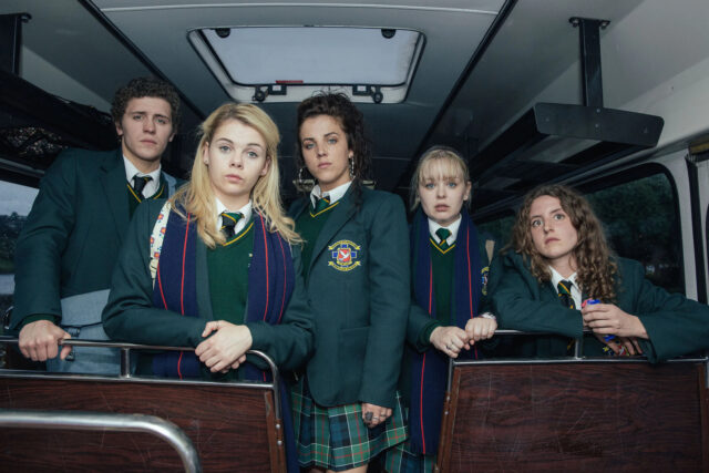Derry Girls TV Series Wallpaper Group Photo of Main Characters in School Uniform on Bus