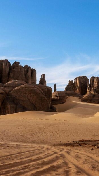 Rock formations rise above the sandy desert landscape under a clear blue sky in Algeria, HD Phone Wallpaper