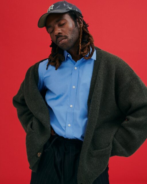 Dev Hynes Fashionable Pose Vibrant Red Background