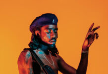 Dev Hynes Guitar Performance Vivid Orange Background Wallpaper
