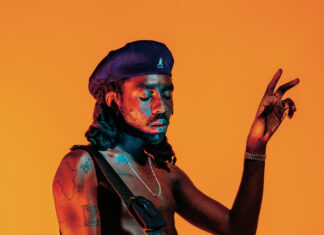 Dev Hynes Guitar Performance Vivid Orange Background Wallpaper