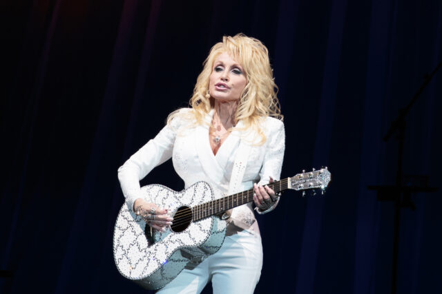 Dolly Parton Performing With Sparkling Guitar Wallpaper