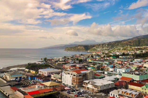 A panoramic view of Dominica city with colorful buildings by the sea under a partly cloudy sky, HD Desktop Wallpaper