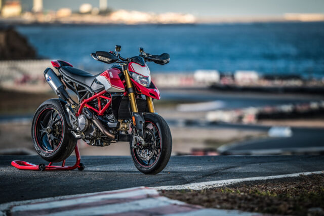 Ducati Hypermotard 950 Red Motorcycle Parked on Race Track Near Ocean Background