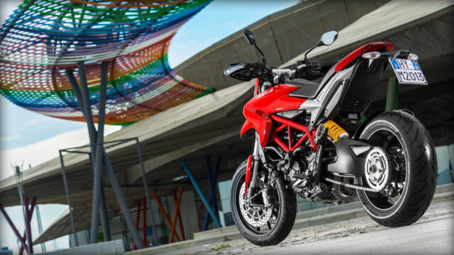 Ducati Hypermotard 950 Red Motorcycle Parked with Modern Colorful Architecture Background